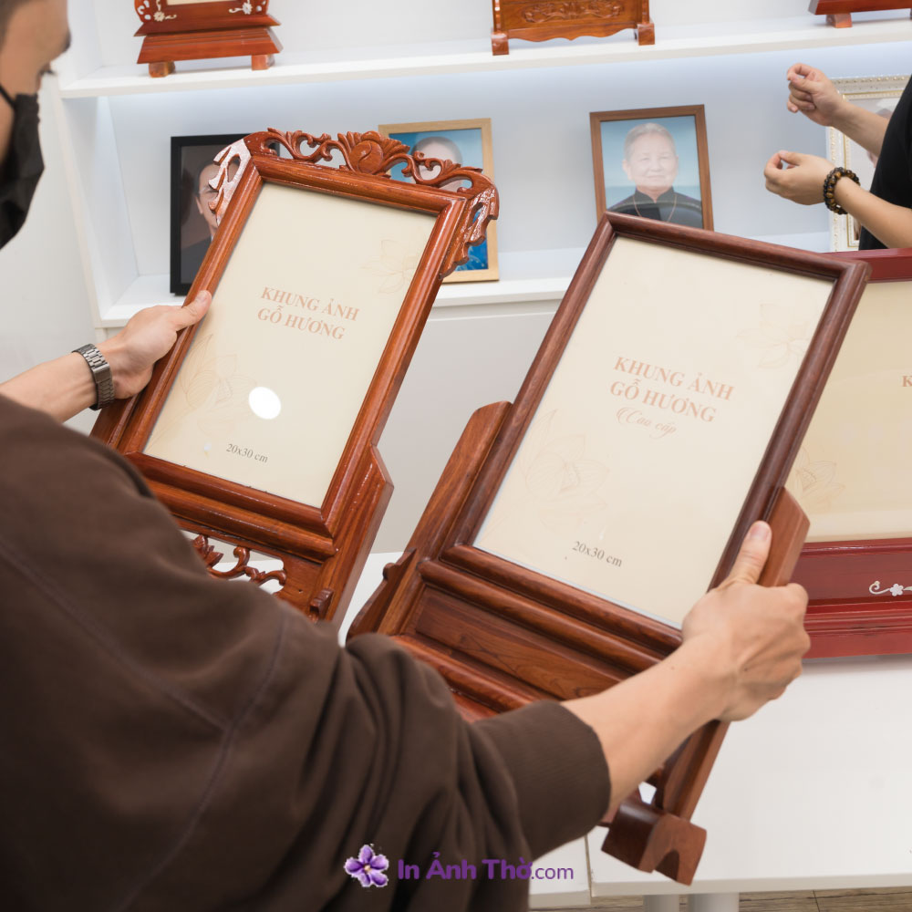 Khách hàng đang so sánh hai mẫu khung ảnh gỗ hương tại cửa hàng In Ảnh Thờ