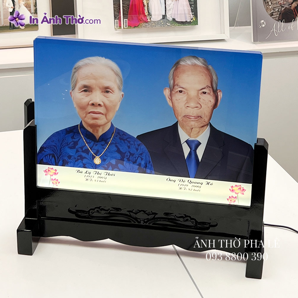 Ảnh thờ pha lê ghép đôi ông bà, bà mặc áo dài xanh, ông mặc vest xanh